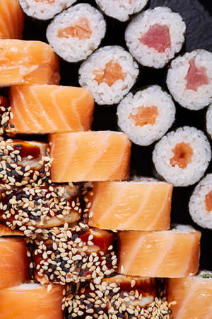 Maki rolls and sushi rolls with salmon sprinkled with sesame seeds and drizzled with a special sauce.の写真素材