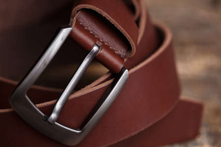 Red mens belt for pants on an aged vintage wooden background. Close up of metal belt buckleの写真素材