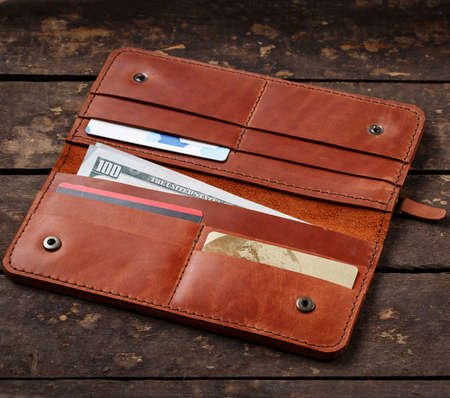 Leather red wallet with money and credit cards on old wooden backgroundの写真素材