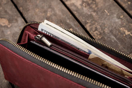 Leather red wallet with money and credit cards on old wooden backgroundの写真素材