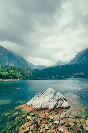 Peaceful mountain lake with big rock in water. Artistic picture.の写真素材