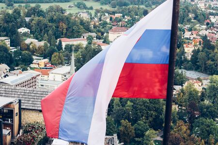 Slovenian national flag fluttering over Lake Bled and townの写真素材
