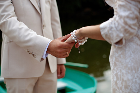 The groom gently holds the bride by the hand, close-upの写真素材