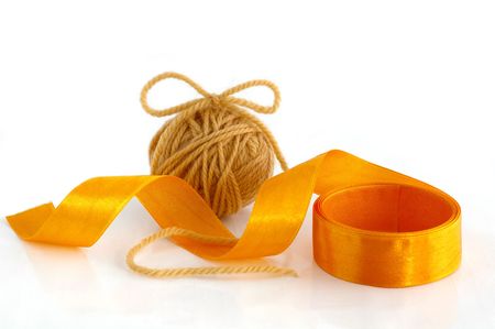 Ball with yarn and ribbon against the white background