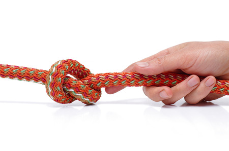 The human hand is holding a rope tied in a knot の写真素材