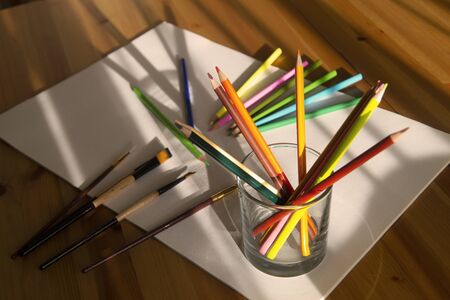 Color pencils and brushes on drawing album with solar patches of light