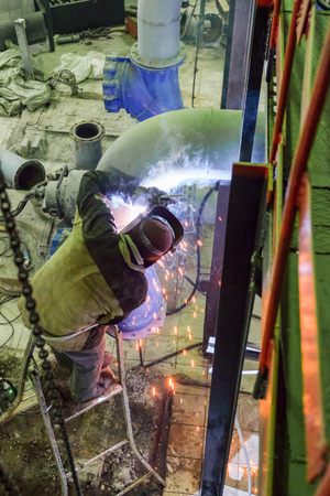 the welder welds metal structures at the construction site