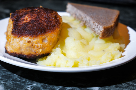 cutlet and mashed potatoes and bread on a plateの写真素材