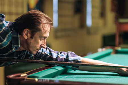a pool player takes aim at the ball