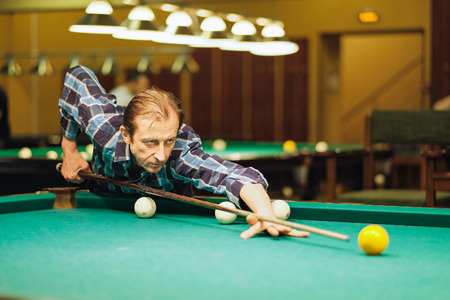 the player takes aim at the ball in Billiards