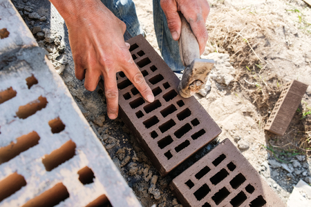 a worker at a construction site puts a brick