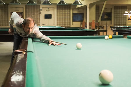 the player takes aim at the ball in Billiards