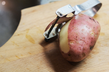 sliced raw potatoes and a knife on a wooden chopping Boardの写真素材