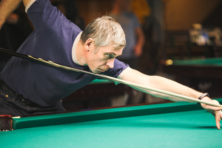 the player takes aim at the ball in Billiards