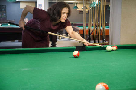 a woman takes aim at a billiard ball