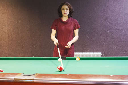 a woman takes aim at a billiard ball