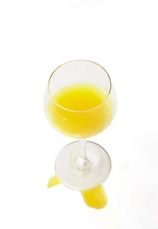 fresh brightly yellow orange juice in glass on a white backgroundの写真素材