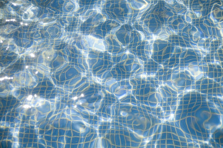 Pure blue transparent water with patches of light from the sun in pool
