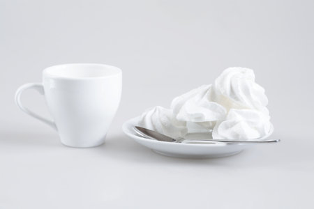 White sweet confectionery on a white saucer and a white cupの写真素材