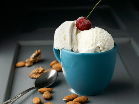 A cup with ice cream balls and a spoon on the table.の写真素材
