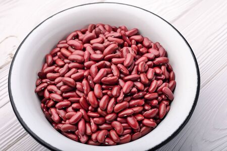Metal bowl of red raw beans on a light wooden background.の写真素材