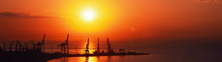 Silhouettes of cranes in the seaport at sunrise panoramic shot.の写真素材