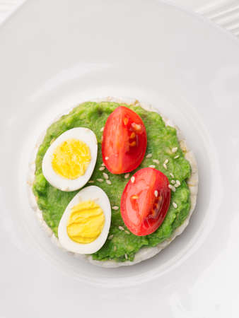 Close up rice cakes with avocado mash and eggs with tomato vertical shot.