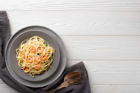Spaghetti shrimp scampi in a plate on a white wooden background top view with copy space.の写真素材