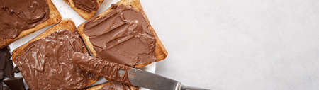 Toast with chocolate-nut paste spread top view with copy space banner.