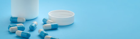 Container and capsules on blue background with copy space banner.の写真素材