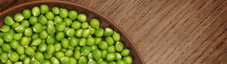 Fresh green peas in a brown plate with copy space banner.の写真素材