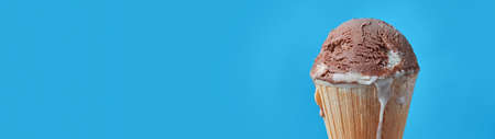 Ball of chocolate ice cream in waffle cone with copy space banner.