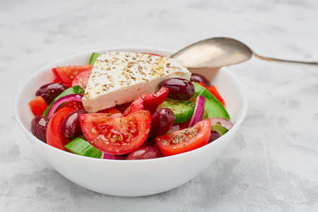 A bowl of classic Greek salad with a piece of feta cheese.の写真素材
