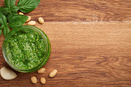Basil pesto in bowl and ingredients on wooden background with copy space top viewの写真素材