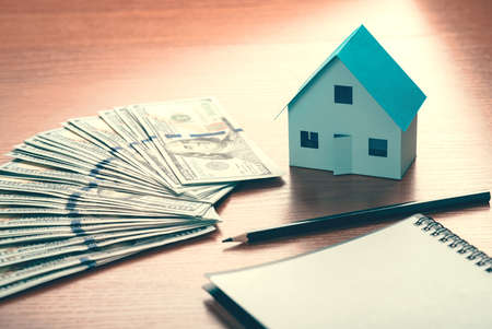 House model and one hundred dollar bills concept of commercial real estate, taxes, rent
