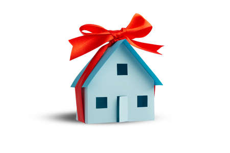 Model of a house tied with a gift ribbon isolated on a white backgroundの写真素材