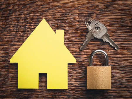 House model and lock with keys on wooden background