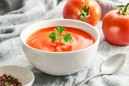 Close up bowl of tomato soup with parsley on tableclothの素材 [FY310187754351]