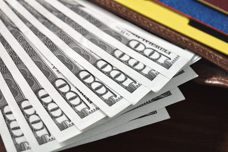 Close-up of one hundred dollar bills protruding from a wallet lying on a table.の写真素材