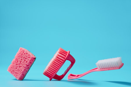 Flying sponge and brushes for cleaning on a blue background with copy space. Studio shot.の写真素材