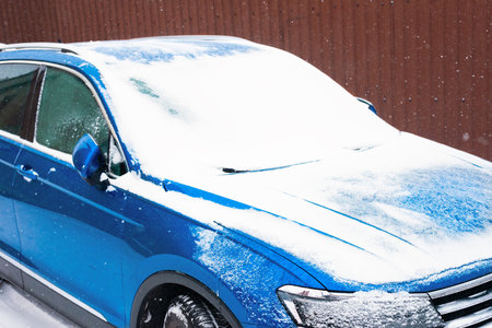 Blue modern car covered with snow during a snowfall in the winter season.の写真素材