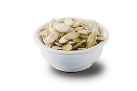 Bowl of shelled raw pumpkin seeds isolated on white background.の写真素材