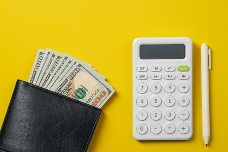 Wallet with cash dollars and calculator, concept of personal finance, savings and budget planning.の写真素材