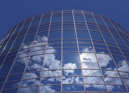 Windows of skyscraper with reflections against blue sky