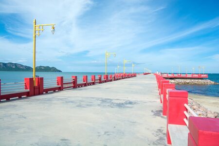 Long red pier or a bridge to the sea with blue sky at Hua-Hin District, Thailandの写真素材