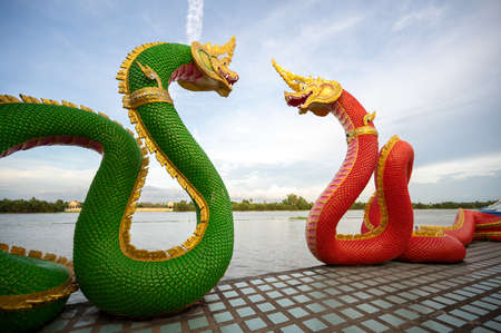 Great Naga green and orange statue standing near the river on the evening at Wat Saman Rattanaram Temple in Chachoengsao Province of Thailand.の写真素材