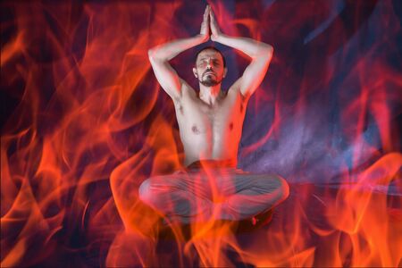 A man sits in a lotus position. Male European 40-45 years old. A man is engaged in meditation. The man raised his arms above his head. Magic and occultism.の写真素材