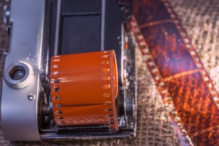 Old film camera. The film is negative color. Developed film. fabric background from canvas. Artistic lighting.の写真素材