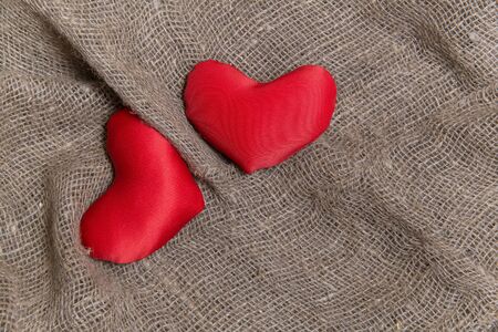 Two red hearts on a rough cloth. Scrim. Valentine's day concept.の写真素材