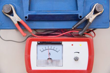 The old car battery is charging. Indicator with an arrow. Charger Terminals. Blue color. Space for...